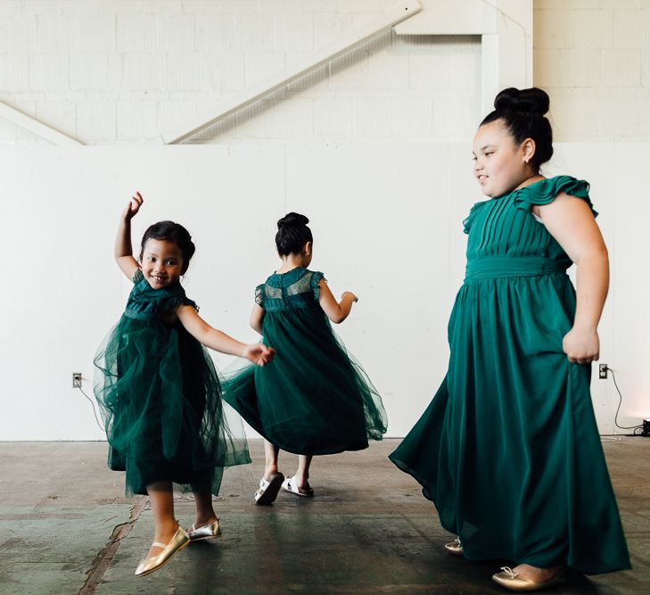 Flower girls in dark green dresses dancing at Industrial wedding