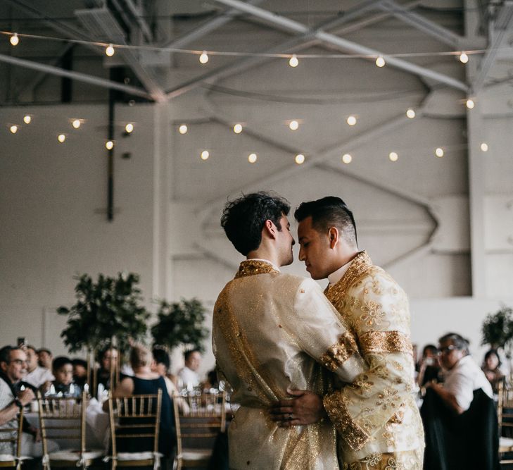 Groom and groom dancing in traditional Cambodian outfits  at their airplane hangar wedding