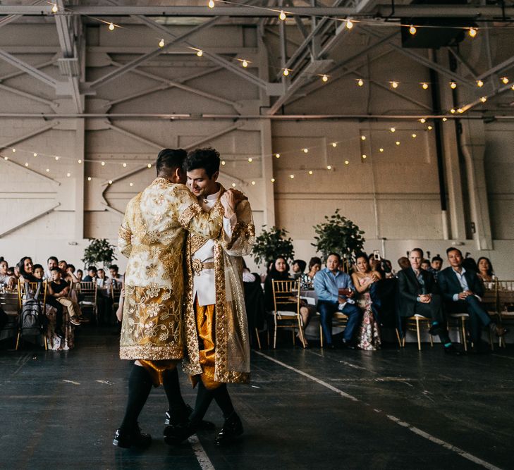 Groom and groom dancing in traditional Cambodian outfits  at their industrial wedding