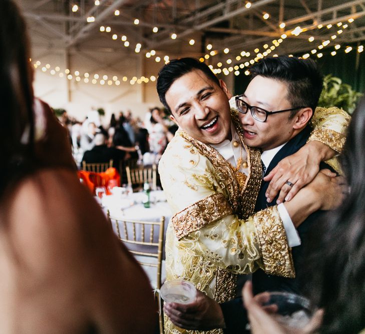 Groom in traditional Cambodian outfit hugging his guest