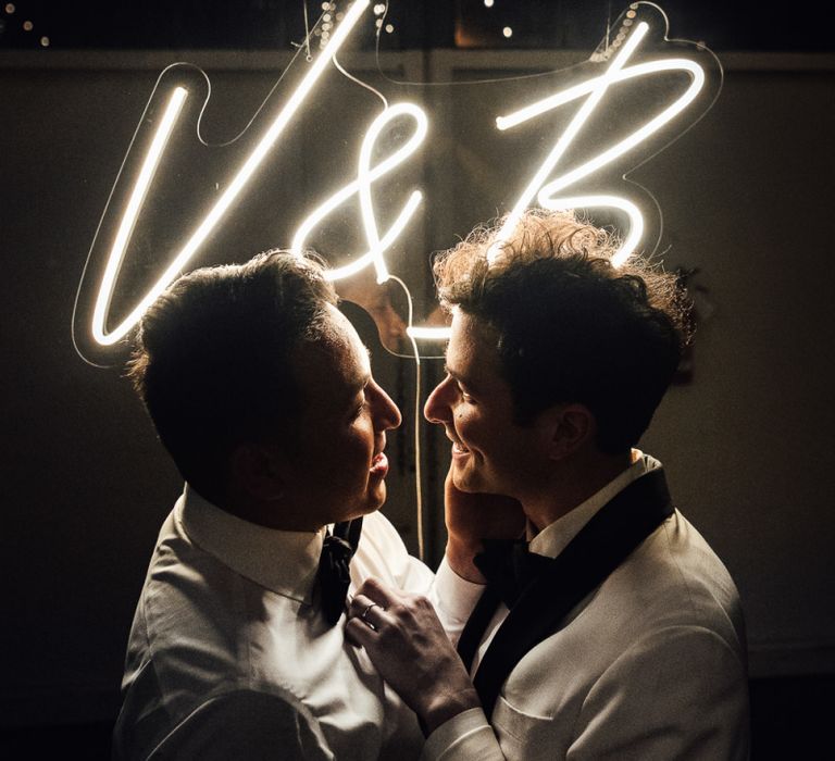 Intimate groom and groom portrait in front of a personalised neon sign