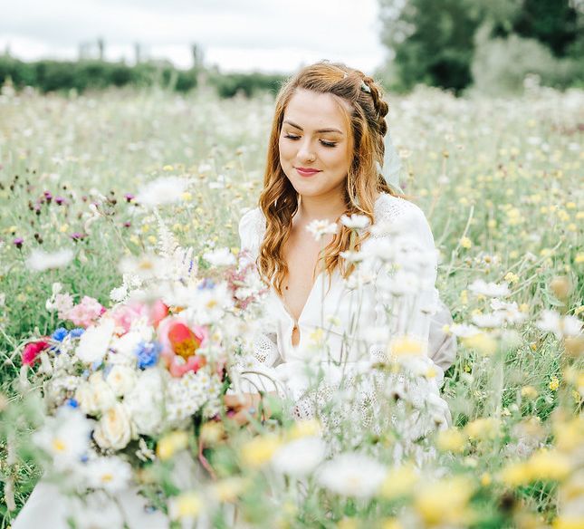 Boho bride with braid sitting in a meadow -  wedding ideas for summer