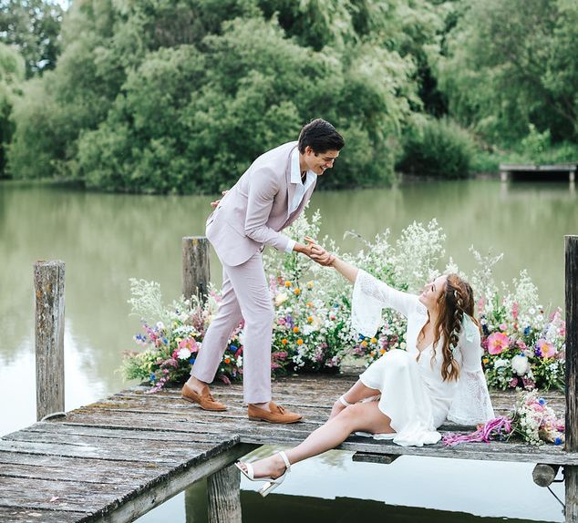 Groom in pink suit helping his bride up