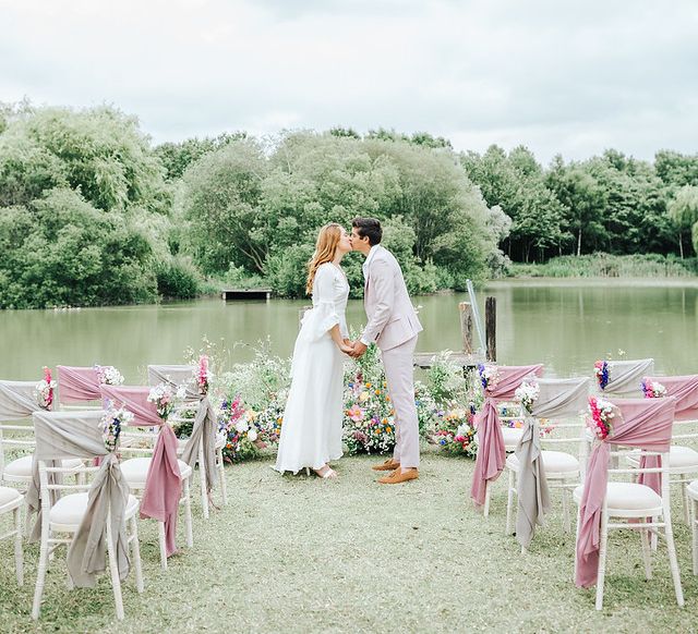 Boho bride and groom kissing at the flower filled altar - wedding ideas for summer