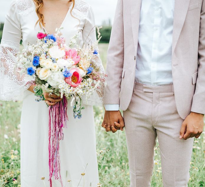 wedding ideas for summer including a pink suit and colourful bridal bouquet