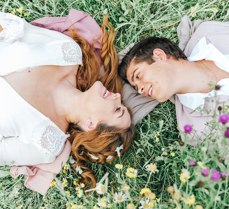 Bride and groom laying in a meadow