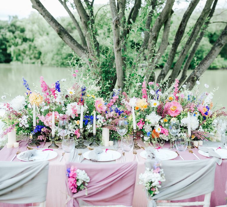 Colourful outdoor dining table with chiffon chair back decor and wildflower centrepiece