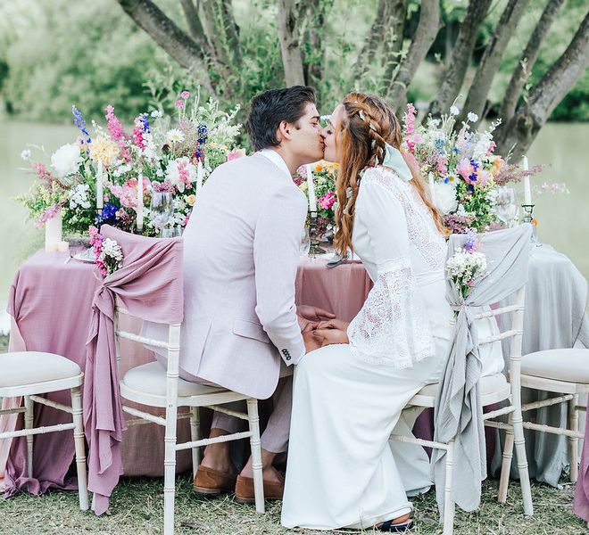 Intimate wedding photograph of the bride and groom kissing at the dining table