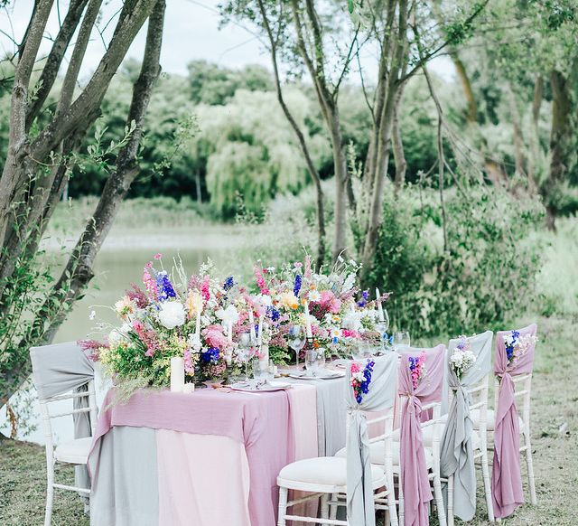 Outdoor reception table filled with floral centrepiece and chiffon table cloth