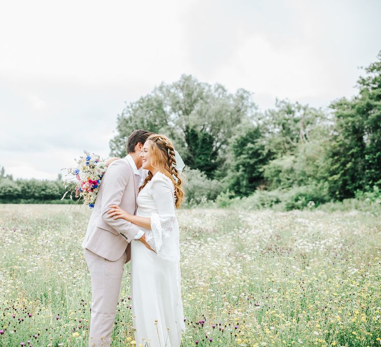 Boho bride and groom kissing in a meadow