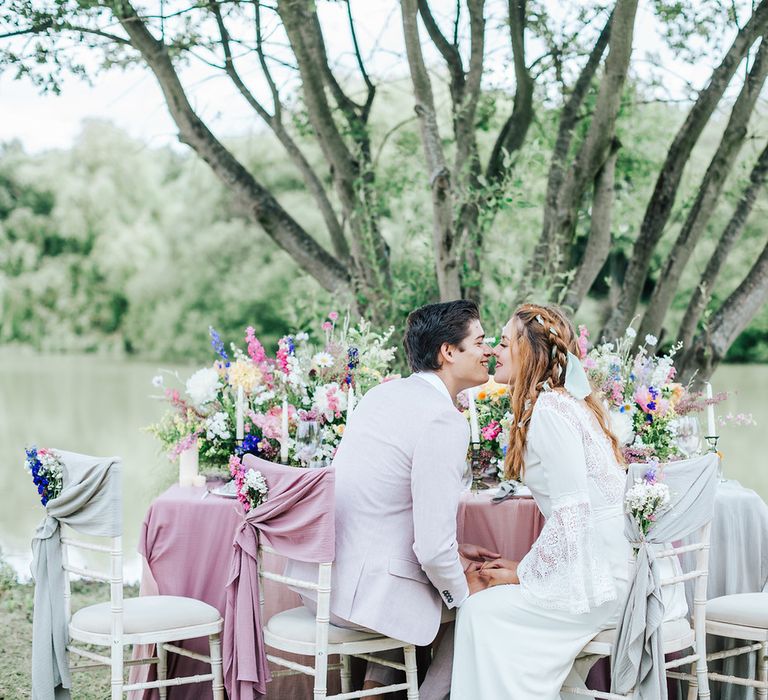 Bride and groom kissing at the outdoor reception table - wedding ideas for summer