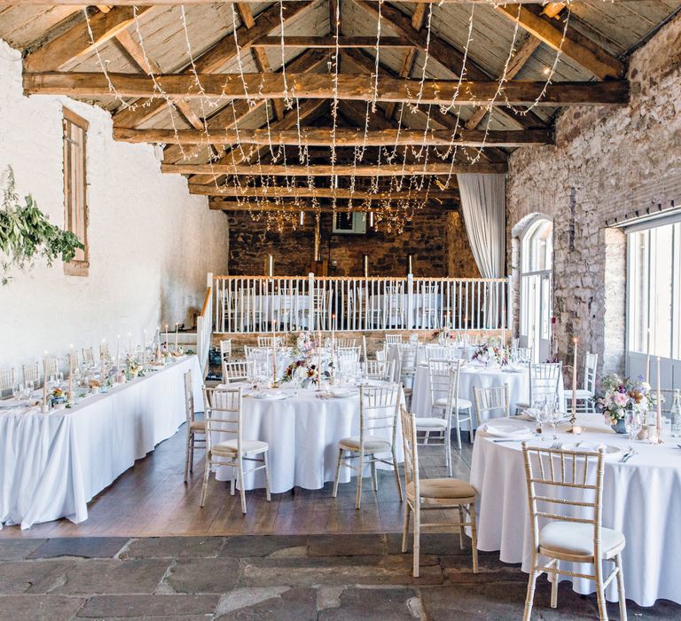 Barn Wedding Reception Decor with Exposed Brick and Fairy Lights Hanging From The Rafters