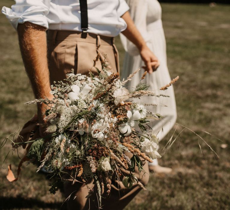 Groom in braces holding a wildflower wedding bouquet