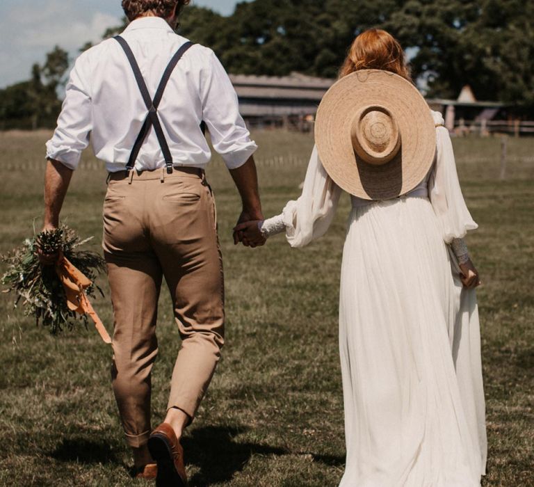 Boho bride and groom holding hands at Wickerwood Farm