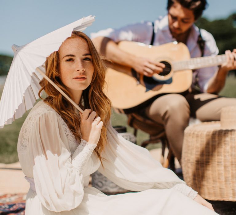 Bride in long sleeve wedding dress holding an umbrella