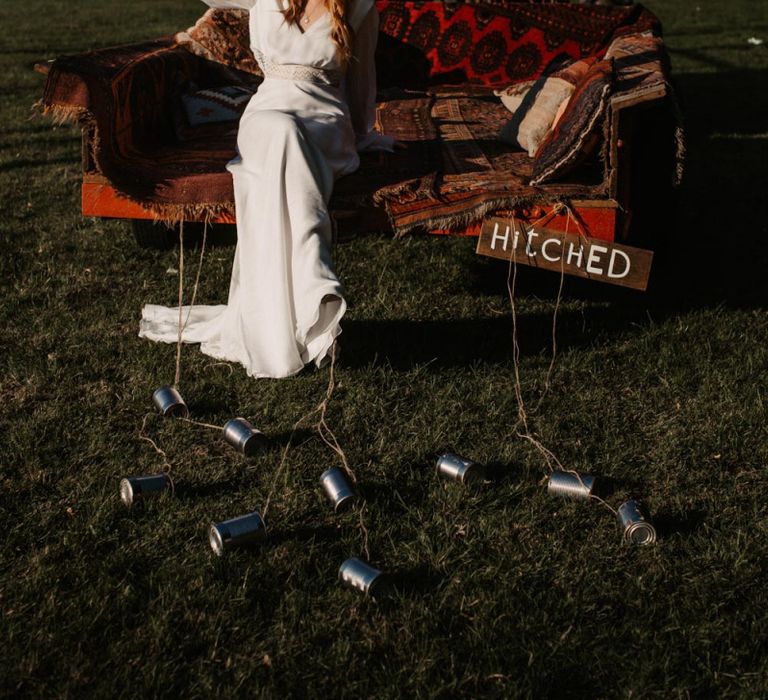 Boho bride sitting on the back of a trailer at Wickerwood Farm wedding