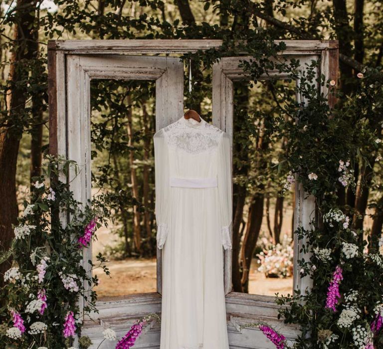 Boho wedding dress with high neck and long sleeves hanging up on wooden doors