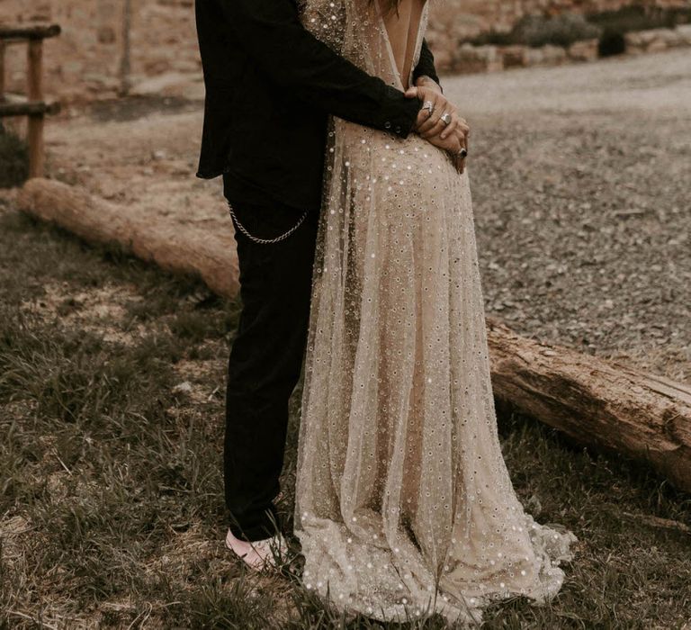 Bride in Backless Gold Sequin Wedding Dress and Groom in Black Fedora Hat Hugging