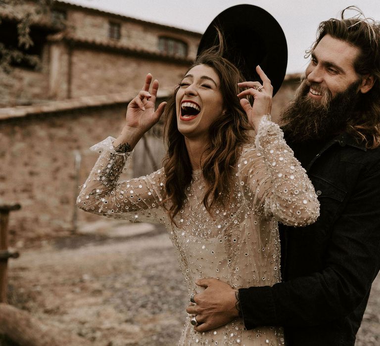 Bride in Gold Sequin Wedding Dress and Groom in Black Fedora Hat Laughing