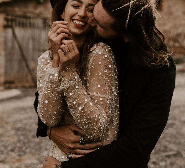 Bride in Gold Sequin Wedding Dress and Groom in Black Fedora Hat Embracing