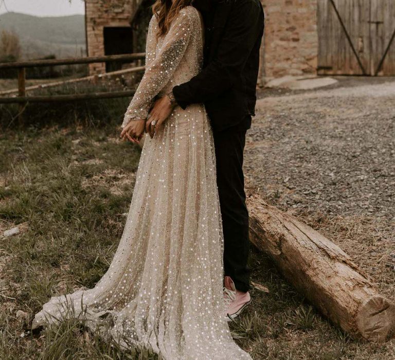 Bride in Gold Sequin Wedding Dress and Groom in Black Hugging at This Must Be The Place Barcelona Wedding Venue