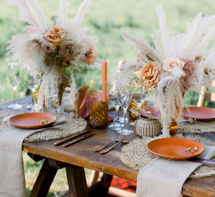 Intimate Tablescape with Ratan Place Setting with Gold Cutlery, Orange Candles and Dried Flowers