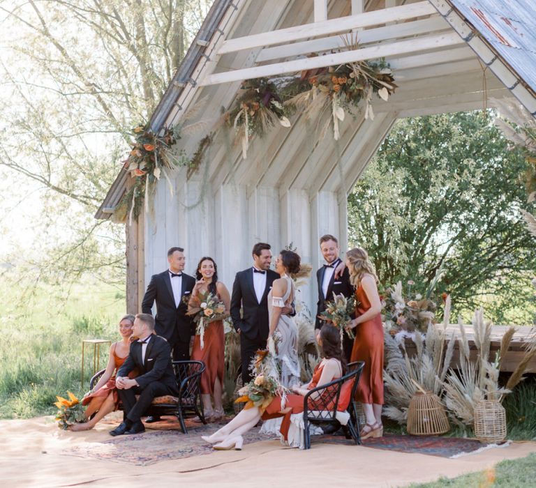 Wedding Party Portrait with Bridesmaids in Rust Dresses, Groomsmen in Tuxedos and Bride in Rue De Seine Boho Wedding Dress