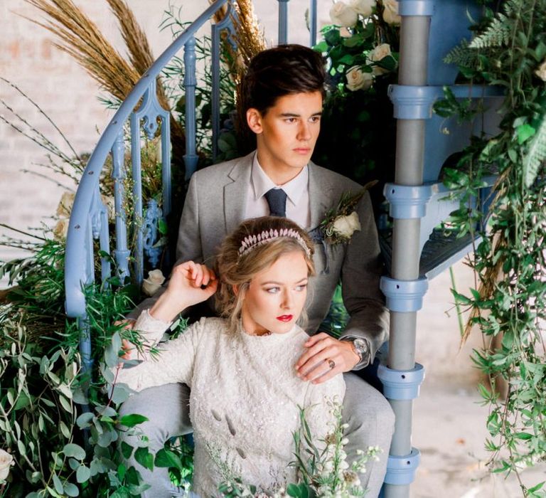 Bride and Groom Sitting on a Blue Spiral Staircase Surrounded by Winter wedding Flower