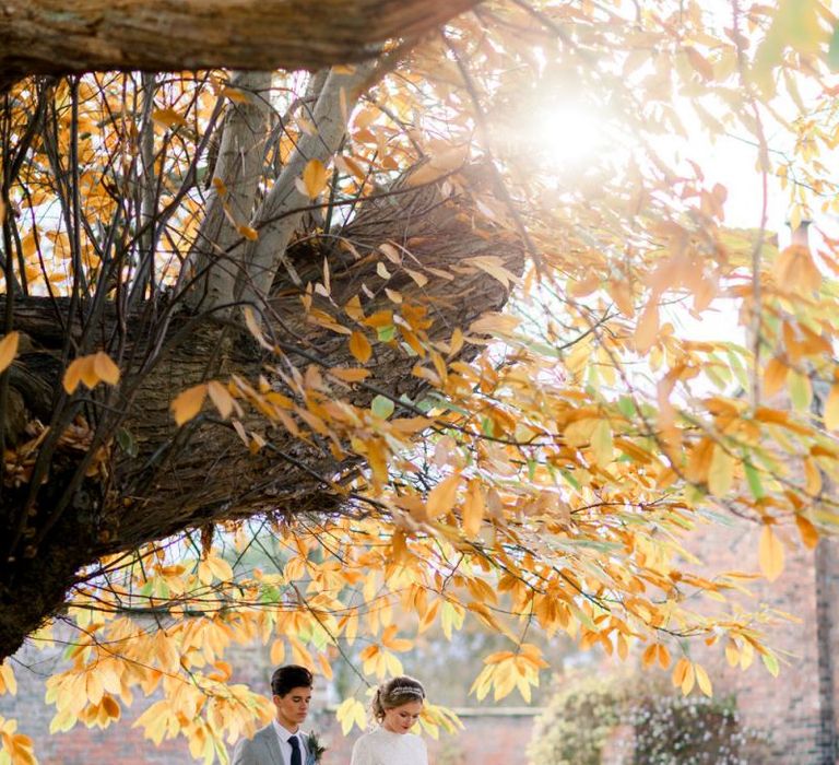 Bride and Groom Holding Hands Amongst the Fallen Autumn Leaves