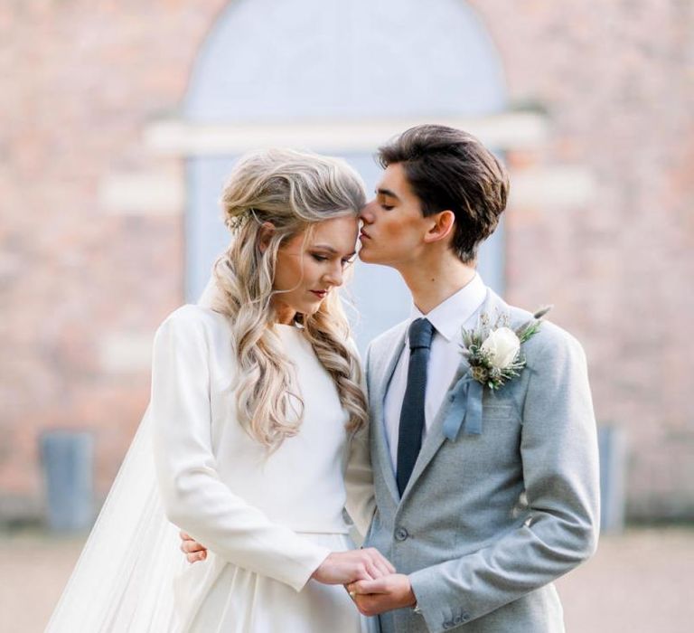 Groom in Grey Suit Kissing Brides Forehead