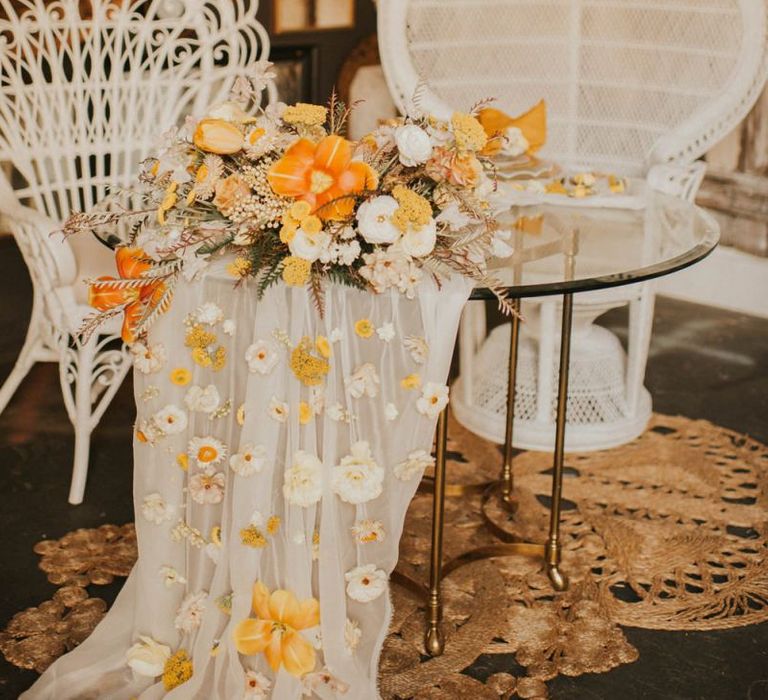 Sweetheart table with peacock chairs and orange bridal bouquet