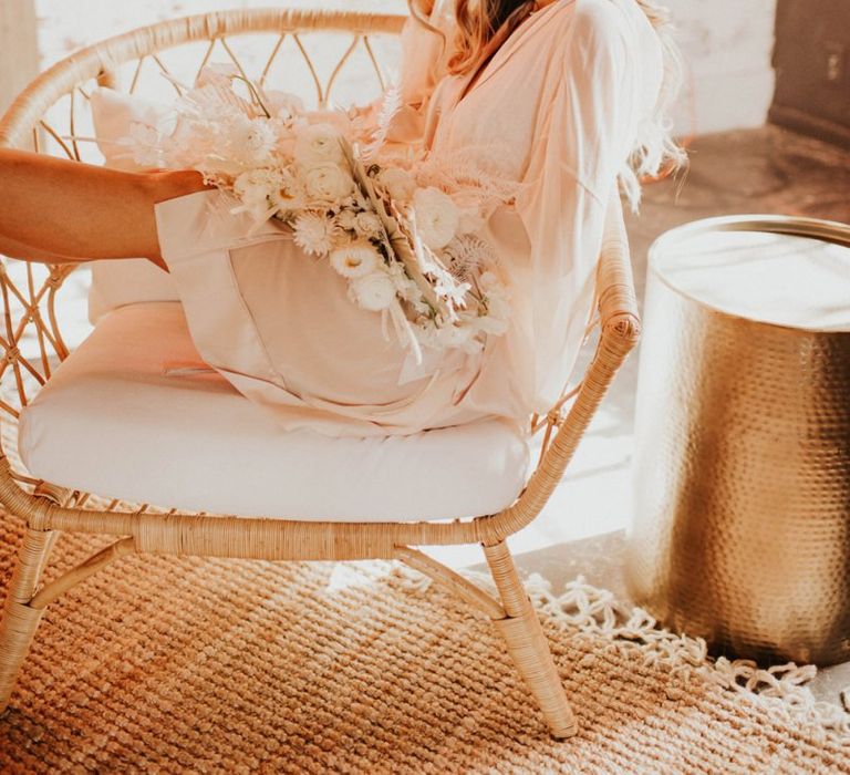 Bride in getting ready robe holding a white boho bouquet