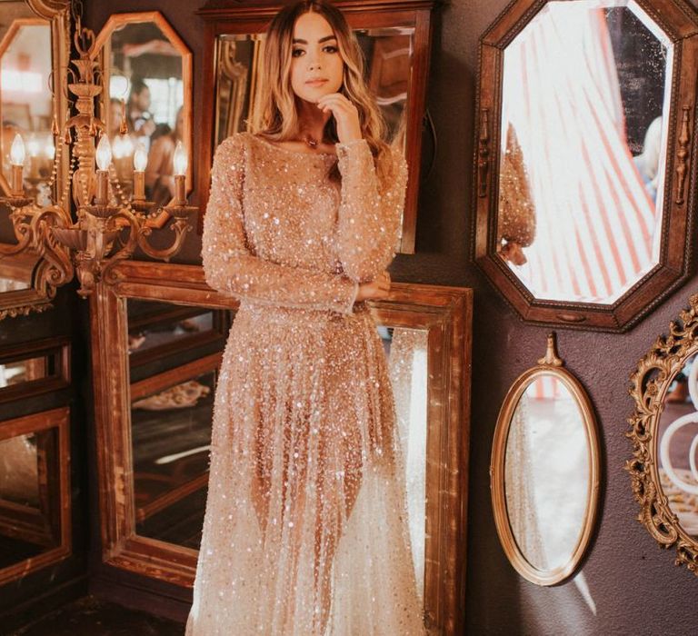 Boho bride in sparkly wedding dress standing in front of ornate mirrors