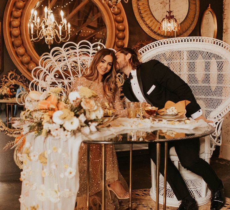 Bride and groom sitting at sweetheart table in peacock chairs