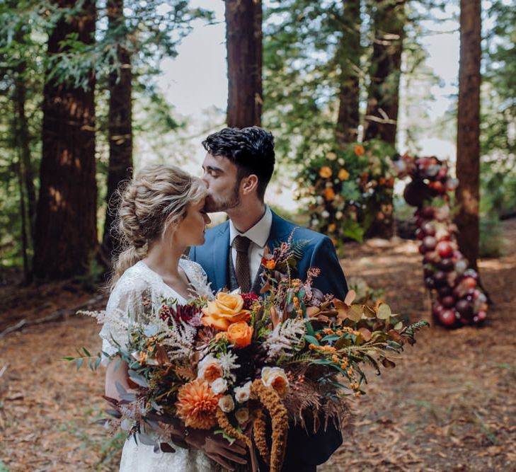 Orange, Red And Brown Autumnal Wedding Bouquet // Balloon And Floral Arch For Wedding Ceremony At Patrick's Barn Woodland Industrial Wedding Venue With Grazing Board Style Food Images By Brigitte &amp; Thierry Photography