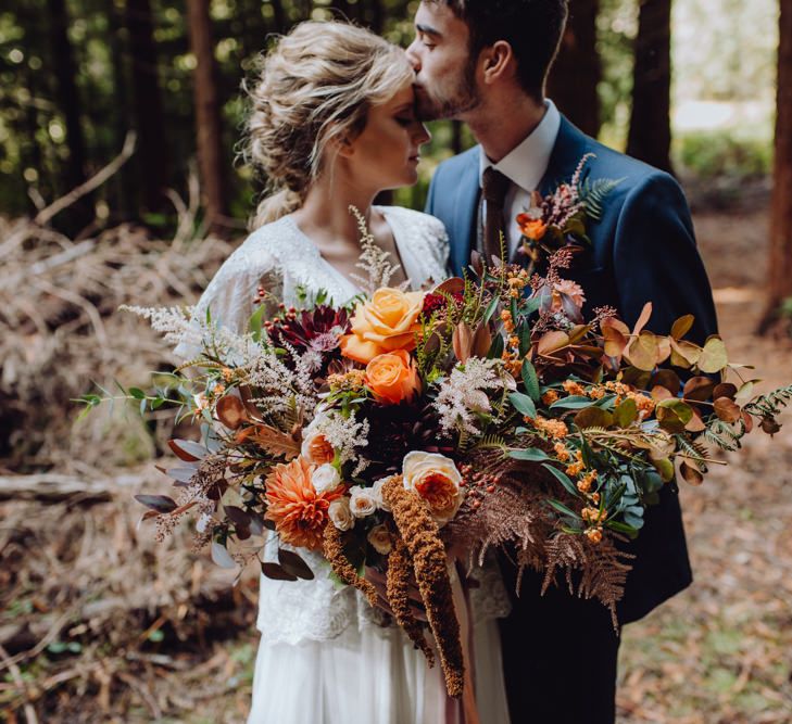 Orange, Red And Brown Autumnal Wedding Bouquet // Balloon And Floral Arch For Wedding Ceremony At Patrick's Barn Woodland Industrial Wedding Venue With Grazing Board Style Food Images By Brigitte &amp; Thierry Photography