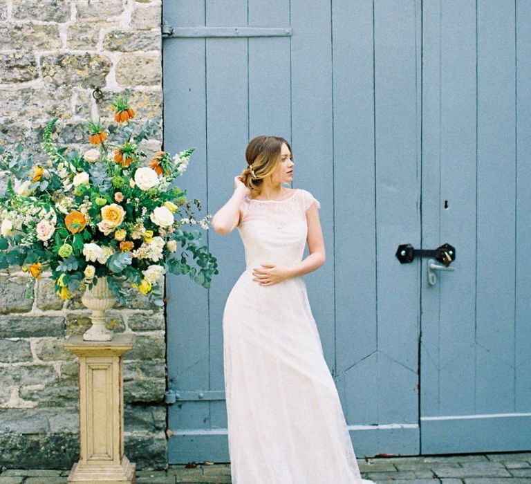 Beautiful Bride in Naomi Neoh Wedding Dress Standing Next to a  Yellow &amp; Green Floral Arrangement