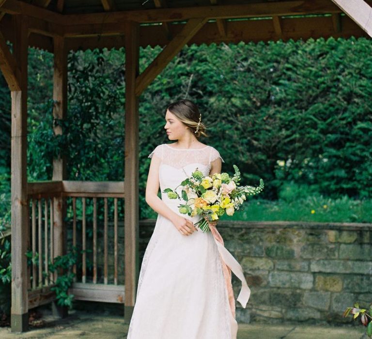 Bride in Naomi Neoh Wedding Dress Holding a Yellow &amp; Green Wedding Bouquet