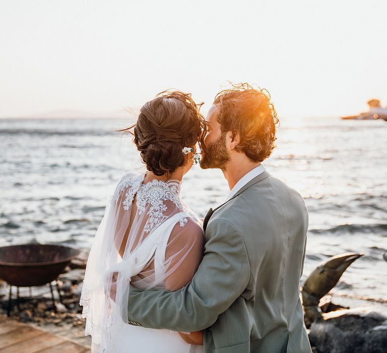 Groom kisses bride in wedding capelet at Mykonos wedding