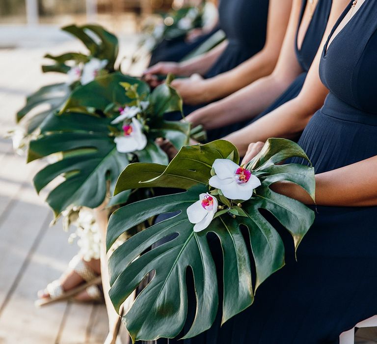 Bridesmaid hold palm leaves as alternative bouquets