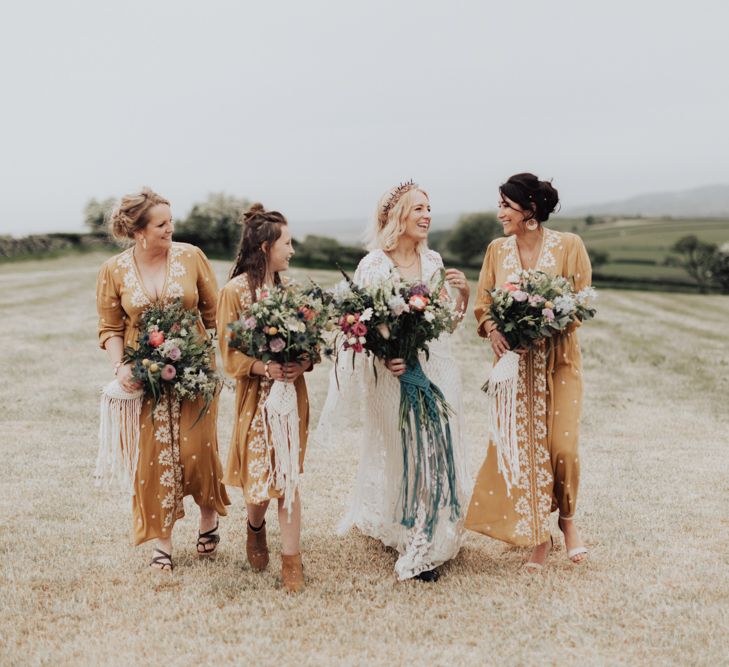 Boho Bridal Party Walking Through the Fields in Lace Rue de Seine Wedding Dress and Yellow Embroidered Dresses