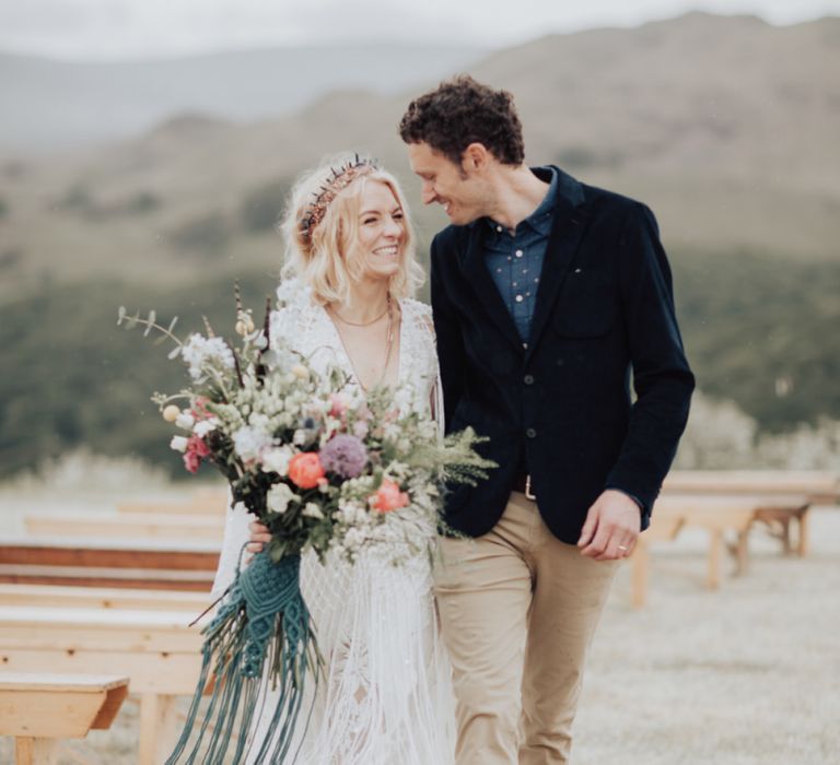 Groom in Navy Blazer and Boho Bride in Rue de Seine Wedding Dress and Crown Holding Hands