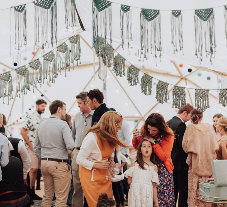 Wedding Guests Enjoying the Party in the Geodome Wedding Reception Decorated with Macrame Bunting