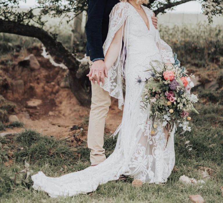 Boho Bride in Rue de Seine Wedding Dress Holding a Spring Wedding Bouquet Posing with Her Groom in Chinos and a Blazer