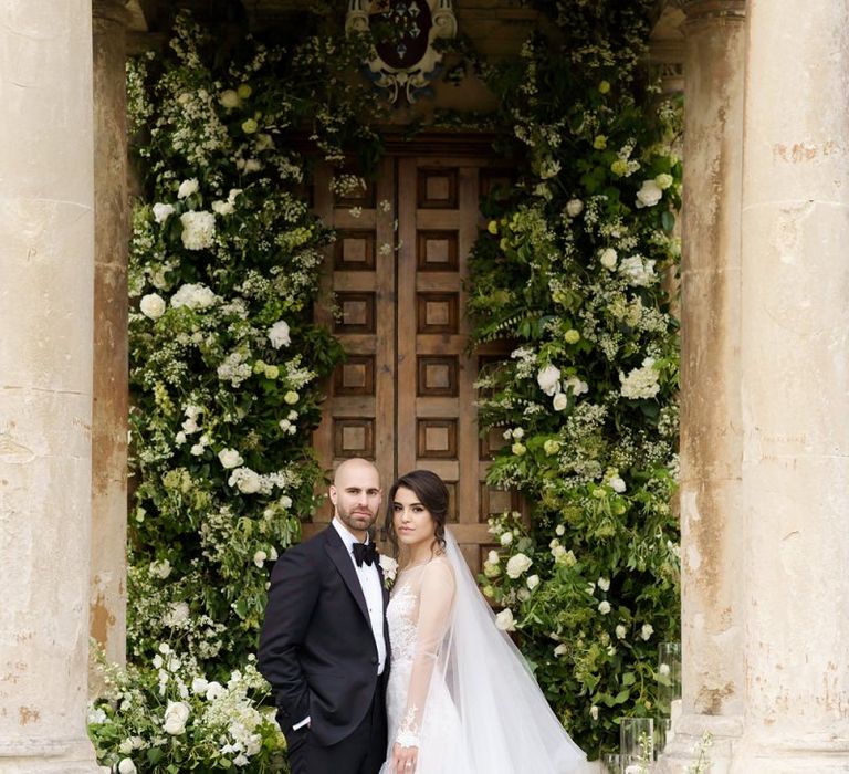 Bride and Groom Portrait by a Large White and Green Floral Arrangement