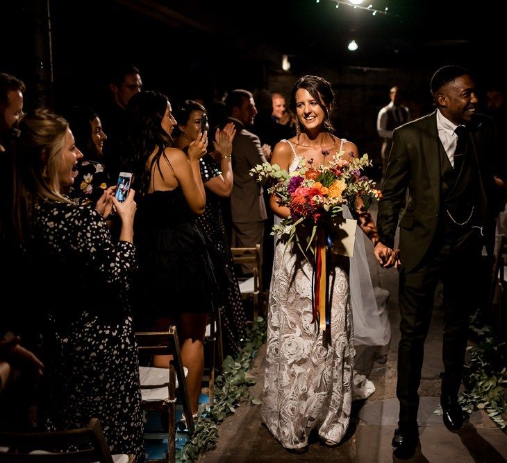 Bride in Grace Loves Lace Rosa wedding dress walking up the aisle with her husband