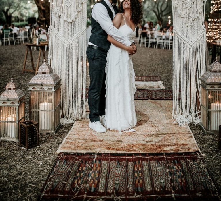 Bride in Max Mara wedding dress with groom under macrame arch