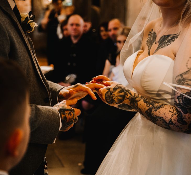 Tattooed Bride in Off The Shoulder Wedding Dress Holding Hands with Her Groom at the Wedding Ceremony