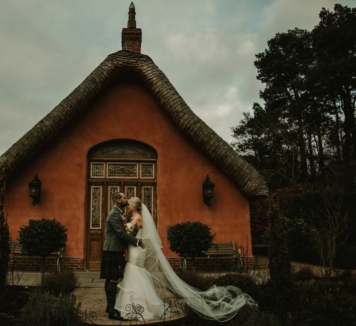 Bride in Fishtail Essense of Australia Wedding Dress and Groom in Tartan Kilt Kissing