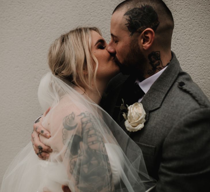 Bride in Essense of Australia Wedding Dress and Groom in Highland Attire Kissing